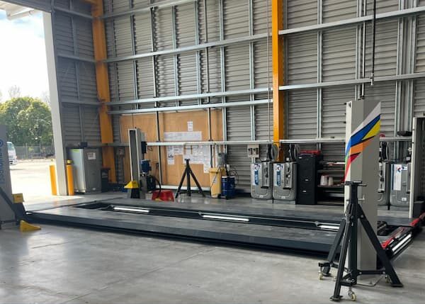 Upgraded Velyen four-post lift installation by EquipSpecs with LED retrofit in heavy-vehicle workshop.