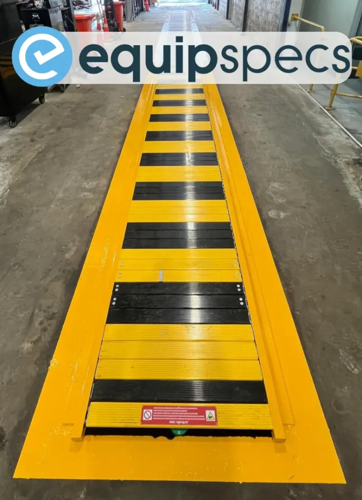 Automatic yellow pit cover installed over a heavy vehicle inspection pit in a commercial workshop, providing a walk-on-safe surface when the pit is not in use.